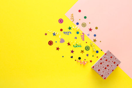 Shiny confetti and box on color background, top view. Space for textの写真素材