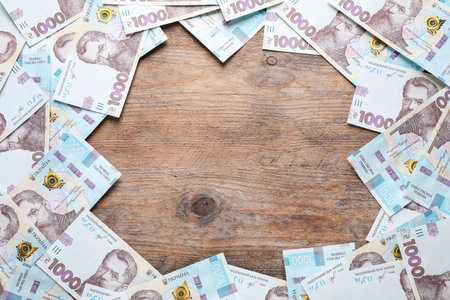 Frame of Ukrainian money on wooden background, flat lay. Space for text