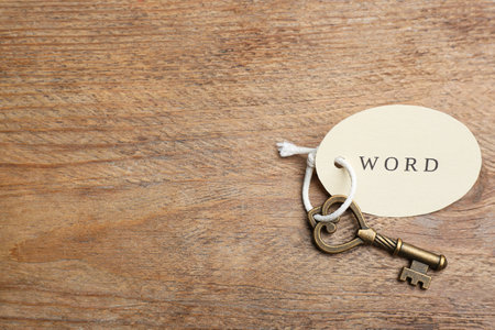 Vintage key with tag on wooden table, top view and space for text. Keyword conceptの写真素材