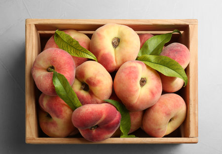 Fresh ripe donut peaches in crate on light table, top viewの写真素材