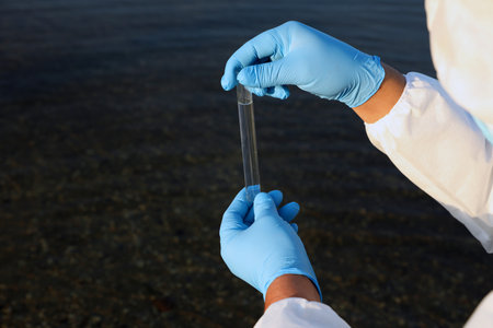 Scientist with test tube taking sample from river for analysis, closeupの写真素材