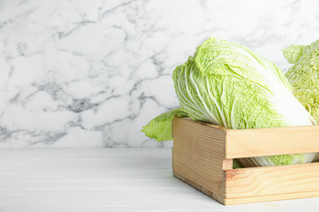 Chinese cabbages in wooden crate on white table. Space for textの写真素材