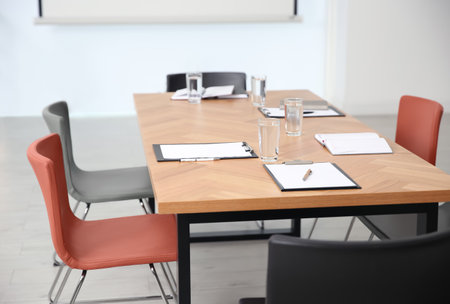 Clipboards and glasses of water on wooden table in modern officeの写真素材
