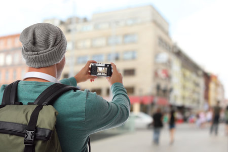 Traveler with backpack taking photo in foreign city during vacation, back viewの写真素材