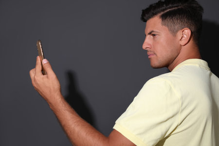 Man unlocking smartphone with facial scanner on gray background. biometric verificationの写真素材