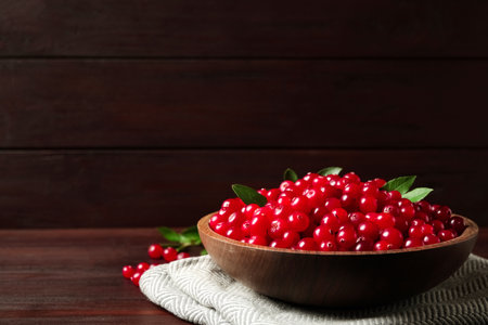 Plate with tasty ripe cranberries on brown wooden table. Space for textの写真素材