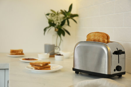 Modern toaster and tasty breakfast on counter in kitchenの写真素材
