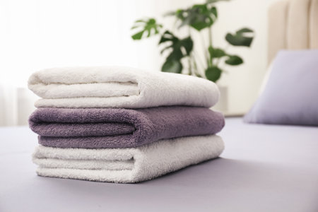 Stack of clean towels on bed indoorsの写真素材