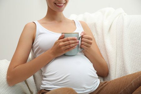 Pregnant woman drinking tea at home, closeupの写真素材