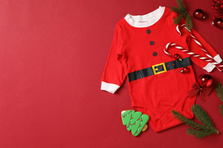 Flat lay composition with cute Christmas baby clothes on red background. Space for textの写真素材