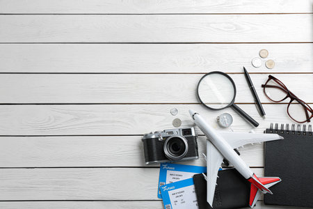 Flat lay composition with toy airplane and travel items on white wooden background. Space for textの写真素材