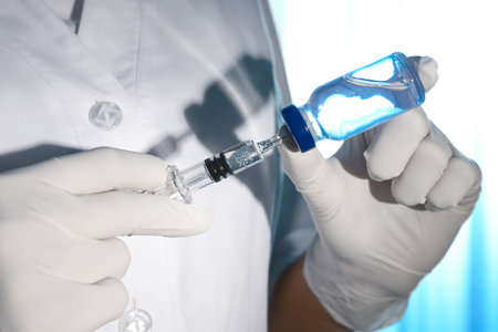 Doctor filling syringe with vaccine from vial on light background, closeupの写真素材