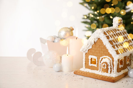 Beautiful gingerbread house decorated with icing and candles on white tableの写真素材