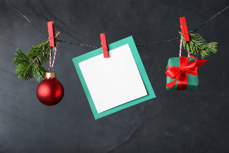 Blank Christmas card and festive decor on rope against black background, space for textの写真素材