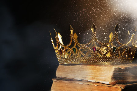 Fantasy world. Beautiful golden crown and old books lit by magic light on table