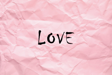 Word Love written on crumpled pink paper, top viewの写真素材
