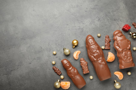Flat lay composition with chocolate Santa Claus candies on grey table, space for textの写真素材