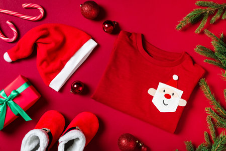 Flat lay composition with cute Christmas baby clothes on red backgroundの写真素材