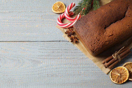 Delicious gingerbread cake, ingredients and Christmas items on wooden table, flat lay. Space for...