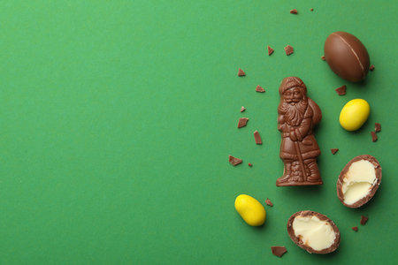 Chocolate Santa Claus candy and sweets on green background, flat lay. Space for textの写真素材