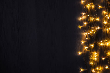 Beautiful glowing Christmas lights on wooden table, top view. Space for textの写真素材