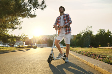 Man with kick scooter in sunny parkの写真素材