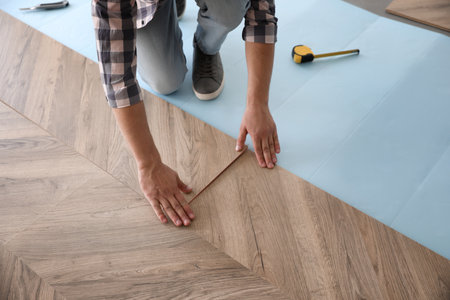 Worker installing laminated wooden floor indoors, closeupの写真素材