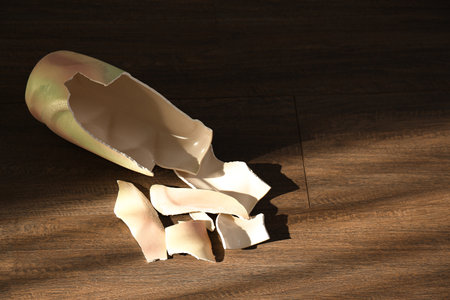 Broken ceramic vase on wooden floor, above view. Space for textの写真素材