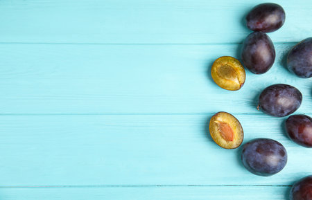 Delicious ripe plums on light blue wooden table, flat lay. Space for textの写真素材