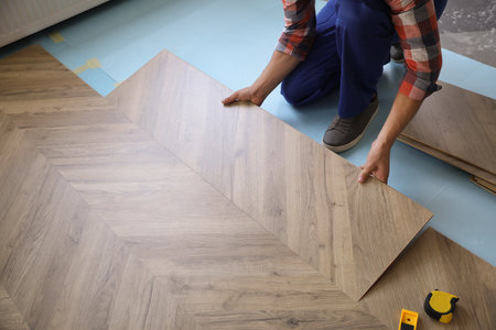 Worker installing laminated wooden floor indoors, closeupの写真素材