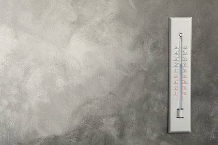 Weather thermometer on gray wall. Space for text