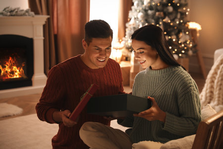 Couple opening gift box in living room with Christmas treeの写真素材