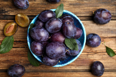 Delicious ripe plums on wooden table, flat layの写真素材