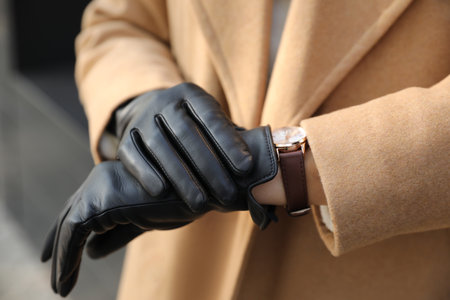 Woman in stylish leather gloves checking time outdoors, closeup of handsの写真素材