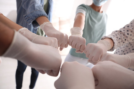 People in white medical gloves joining fists on light background, closeupの写真素材