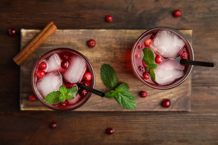 Tasty refreshing cranberry cocktail with mint on wooden table, flat layの写真素材