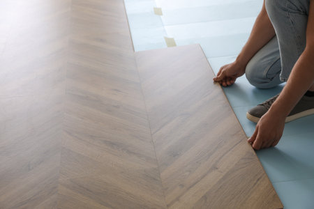 Worker installing laminated wooden floor indoors, closeupの写真素材