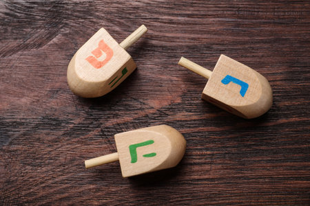 Hanukkah traditional dreidels with letters He, Pe and Nun on wooden table, flat layの写真素材