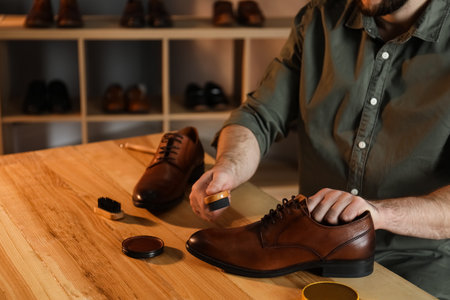 Man taking professional care of brown leather shoes in workshop, closeupの写真素材