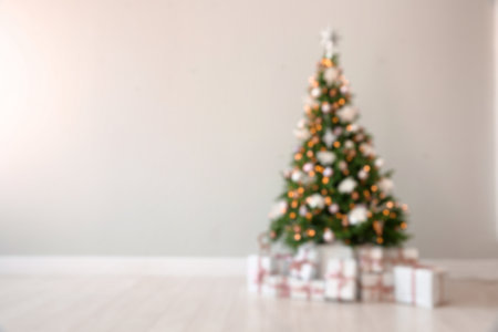 Beautiful decorated Christmas tree and gifts near light wall. Space for textの写真素材