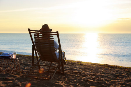 Man relaxing on deck chair at sandy beach. summer holidaysの写真素材