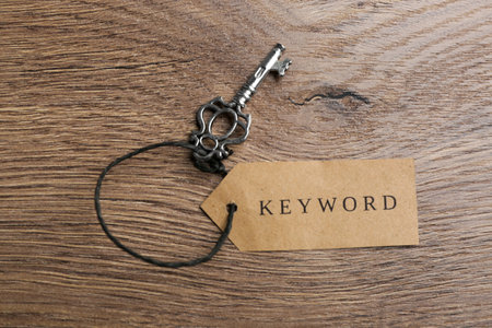 Vintage key and tag wIth word KEYWORD on wooden table, top viewの写真素材