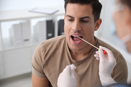 Doctor taking sample for DNA test from man in clinic