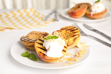 Delicious grilled peaches with ice cream served on white wooden tableの写真素材