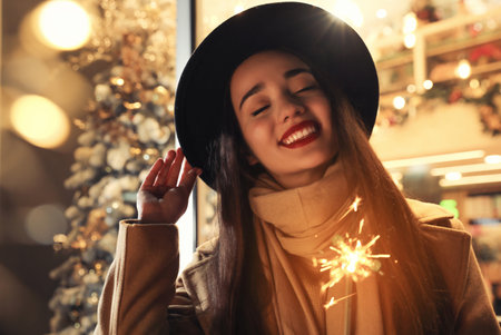 Woman in warm clothes holding burning sparkler on blurred backgroundの写真素材