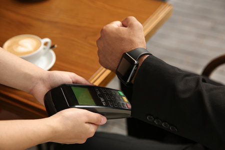 Man making payment with smart watch in cafe, closeupの写真素材