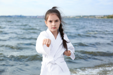 Cute little girl in kimono practicing karate near the riverの写真素材