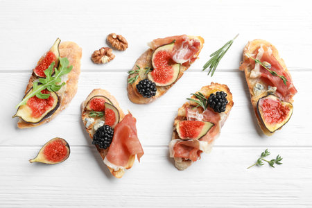 Sandwiches with ripe figs and prosciutto served on white wooden table, flat layの写真素材