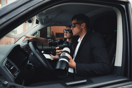 Private detectives with modern camera spying from carの写真素材