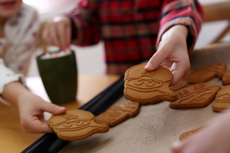 Little children taking tasty Christmas cookies from baking sheet, closeup